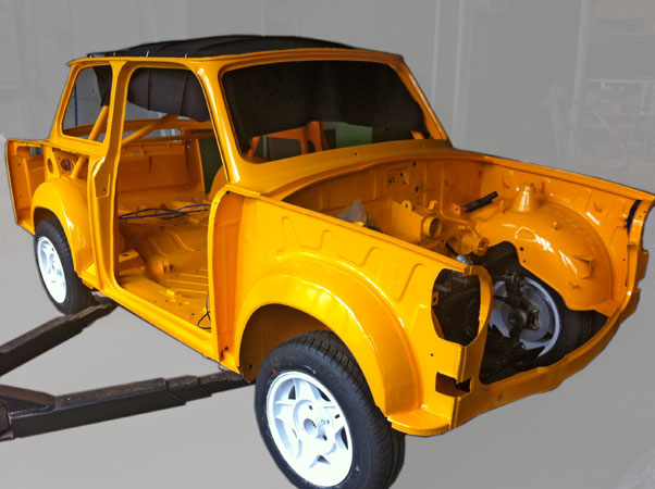 Montagearbeiten. Nach dem 2.mal Sandstrahlen wurde die Karosse Gundiert, eine vollumfängliche Nahtabdichtung durchgeführt und anschließend komplett mit der Wunschfarbe (Melonen-Gelb) lackiert. Dabei wurde der Unterboden, Motorraum und Innenraum fertig lackiert. Das Bild zeigt die Montagearbeit des Spannhimmels, welcher extra von uns entworfen und gefertigt wurde für Trabis mit Käfig.